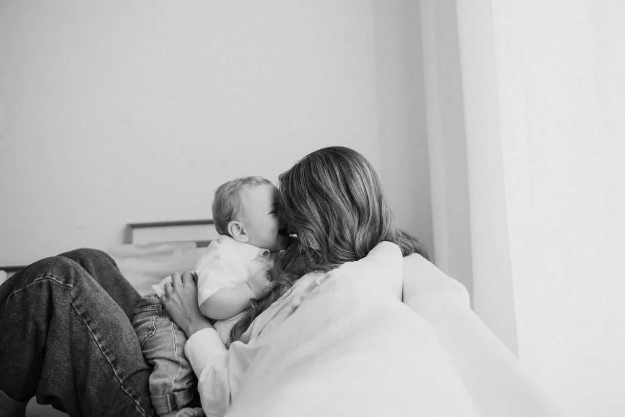 Mãe e bebê na cama, em preto e branco