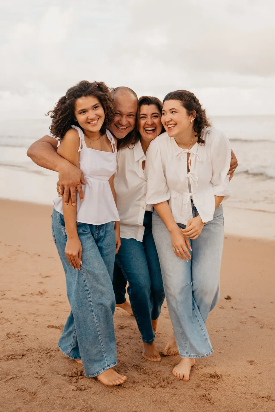 Família abraçada rindo na praia